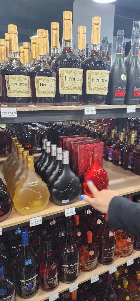 A Trenton Liquors team member pointing out a bottle on the premium cognac shelf